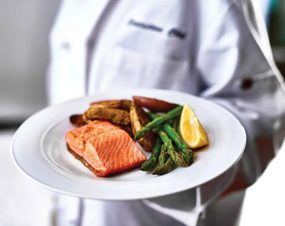 The Peaks at Santa Rita Chef Created Meals, chef delivering a finished dish.