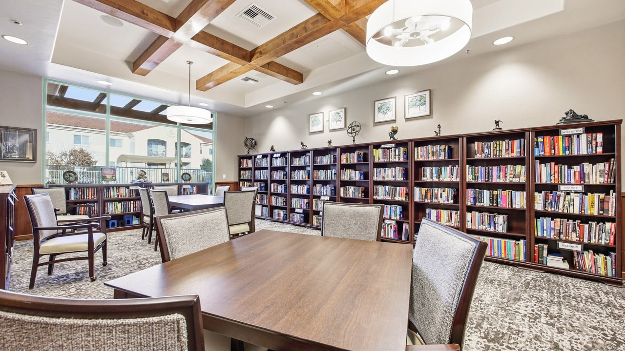 The library at The Peaks at Santa Rita with shelves of books and comfortable seating
